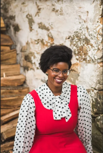 Photo of Interviewee Elizabeth Crowder, a Black woman wearing glasses and a red dress, smiles at the camera.